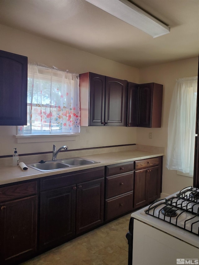 kitchen featuring range, light tile patterned floors, dark brown cabinets, and sink