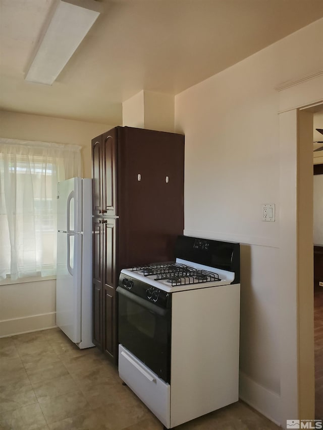 kitchen with dark brown cabinets, white appliances, and light tile patterned floors