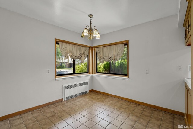 tiled empty room with an inviting chandelier and radiator