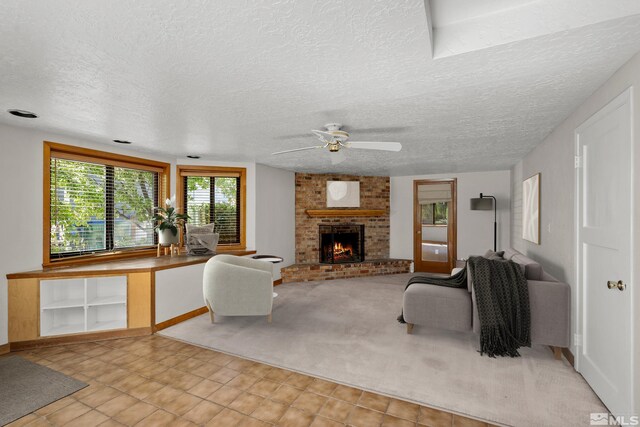 living room featuring ceiling fan, a fireplace, light colored carpet, and a textured ceiling