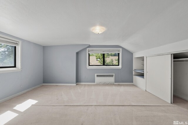 bonus room featuring lofted ceiling, light carpet, and radiator