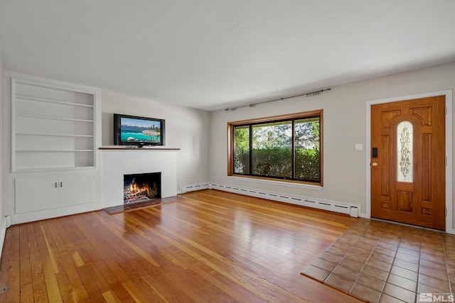 unfurnished living room featuring a fireplace, a baseboard heating unit, built in features, and light wood-type flooring