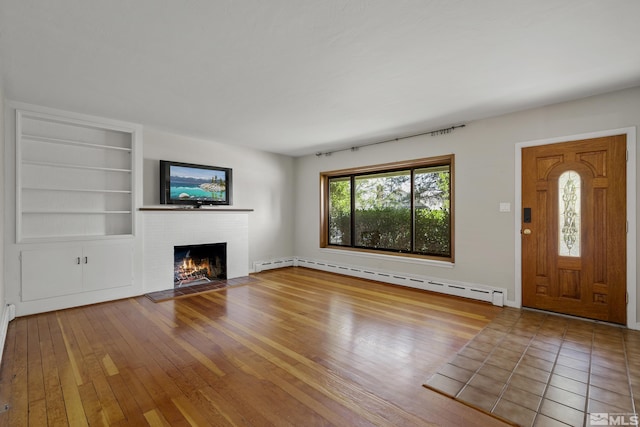 unfurnished living room featuring a baseboard heating unit, hardwood / wood-style floors, built in features, and a fireplace