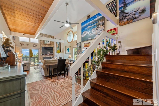 stairs with beam ceiling, wood-type flooring, high vaulted ceiling, and ceiling fan