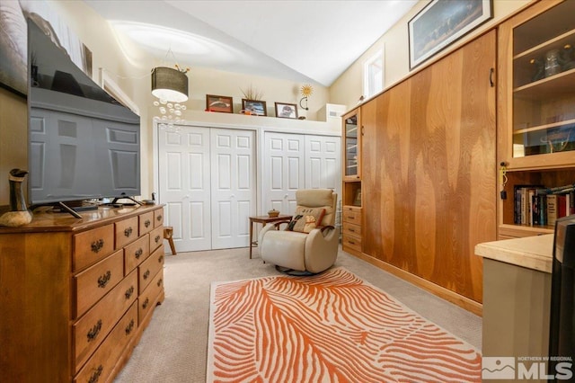 sitting room featuring vaulted ceiling, light carpet, and wood walls