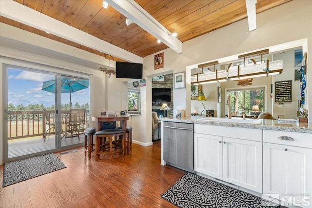 kitchen with dishwasher, white cabinets, light stone counters, wooden ceiling, and beam ceiling