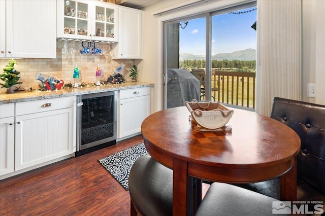 kitchen featuring white cabinetry, a mountain view, light stone counters, and beverage cooler