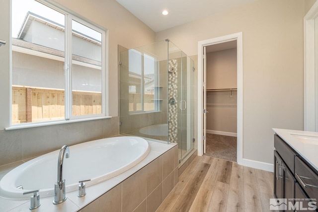 bathroom with wood-type flooring, independent shower and bath, and vanity