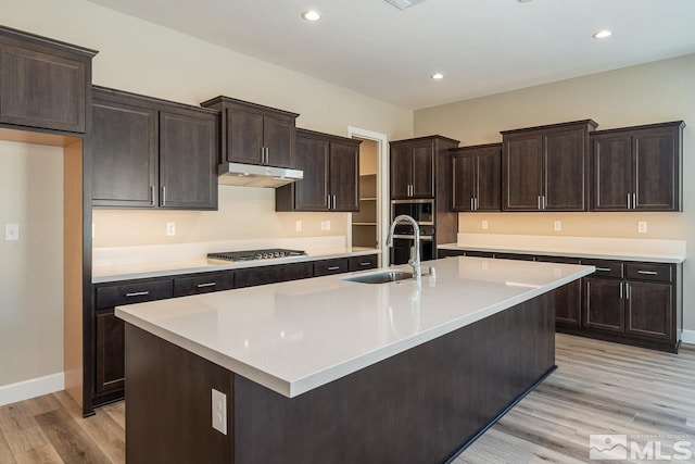 kitchen with sink, dark brown cabinetry, light hardwood / wood-style floors, an island with sink, and stainless steel gas cooktop