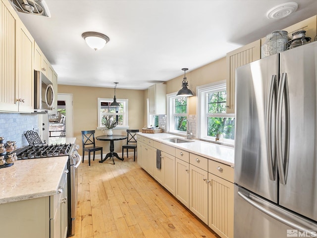 kitchen with stainless steel appliances, tasteful backsplash, sink, and decorative light fixtures