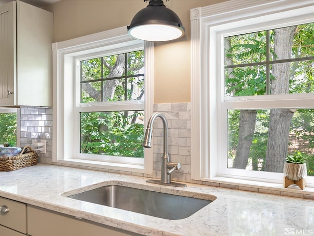 kitchen with tasteful backsplash, sink, and light stone countertops