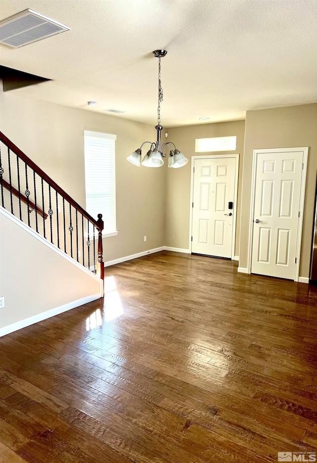 interior space featuring dark wood-type flooring, a textured ceiling, and an inviting chandelier