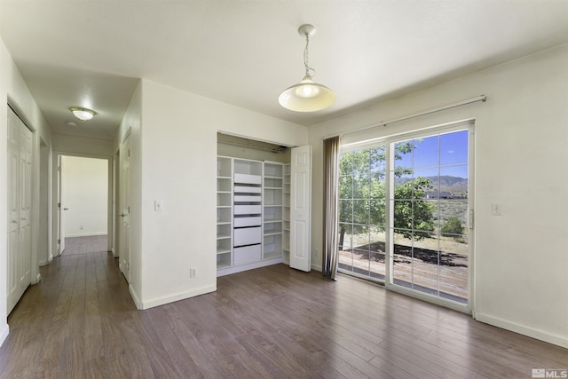 unfurnished bedroom featuring a closet, baseboards, access to exterior, and dark wood-style flooring