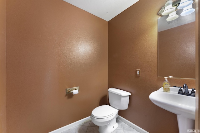 bathroom featuring tile patterned floors, baseboards, toilet, and a sink