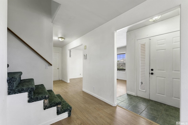 foyer entrance with dark wood-style floors, stairs, and baseboards