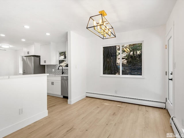 unfurnished dining area with a baseboard radiator, a healthy amount of sunlight, and light wood-type flooring