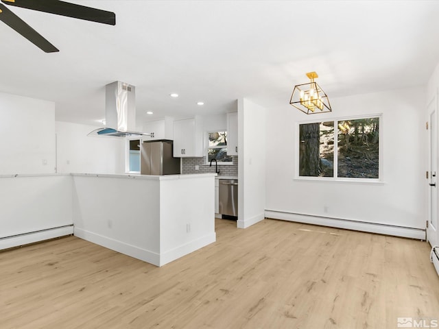 kitchen with appliances with stainless steel finishes, white cabinetry, a baseboard radiator, hanging light fixtures, and island exhaust hood