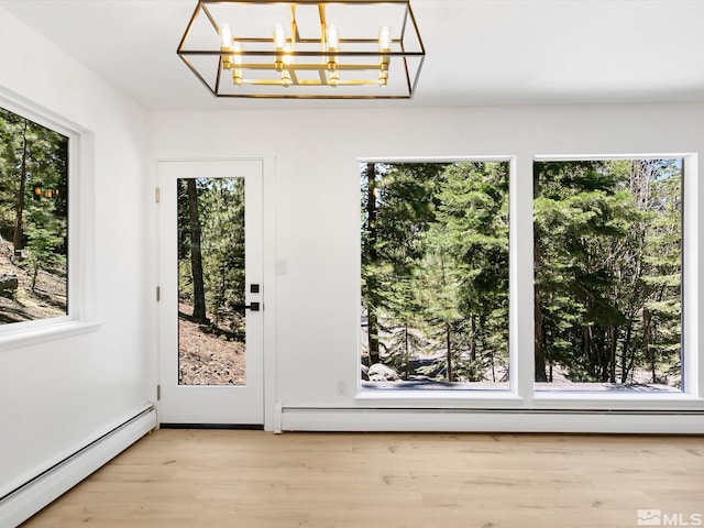 doorway to outside featuring a notable chandelier, plenty of natural light, and baseboard heating