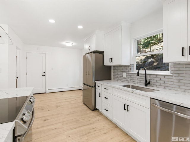 kitchen featuring sink, a baseboard radiator, stainless steel appliances, light stone countertops, and white cabinets