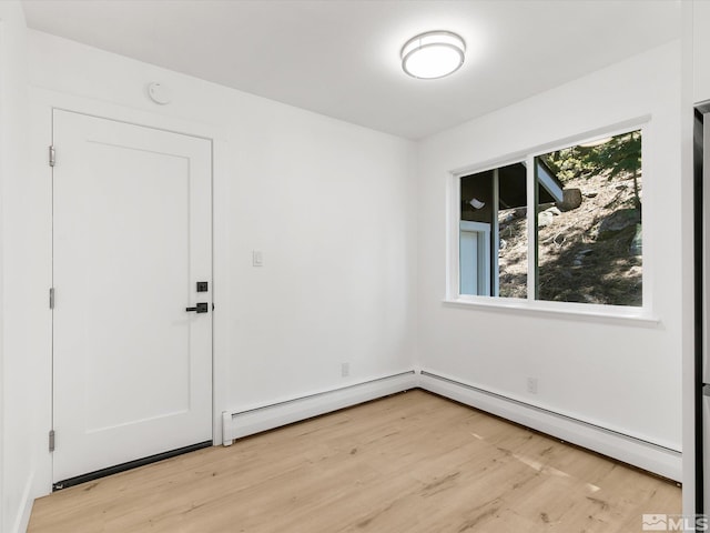 spare room with a baseboard radiator and light wood-type flooring