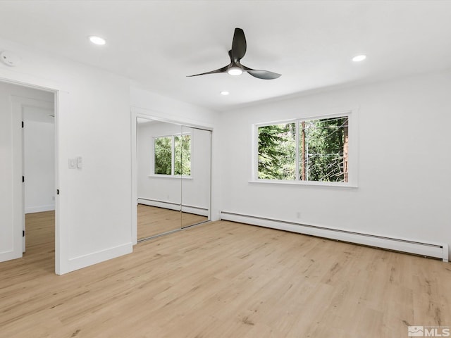 unfurnished bedroom with a baseboard radiator, light hardwood / wood-style floors, ceiling fan, and a closet