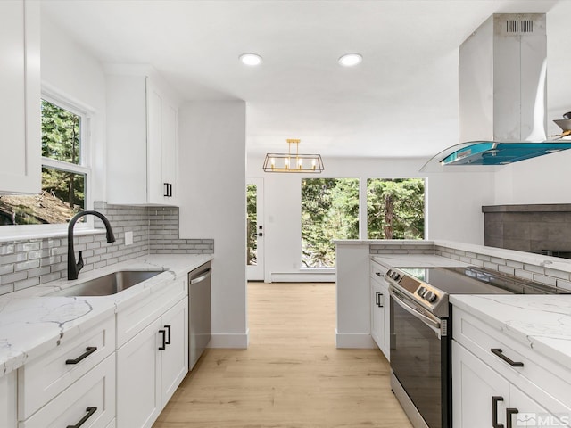 kitchen with sink, white cabinetry, island range hood, appliances with stainless steel finishes, and light stone countertops