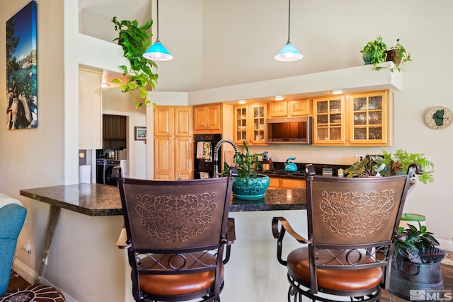 kitchen featuring glass insert cabinets, washer / clothes dryer, hanging light fixtures, and a breakfast bar area