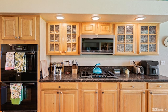 kitchen with black appliances, light brown cabinetry, dark countertops, and glass insert cabinets