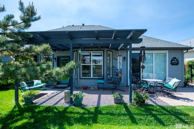 rear view of house featuring a shingled roof, a lawn, a patio area, and a pergola