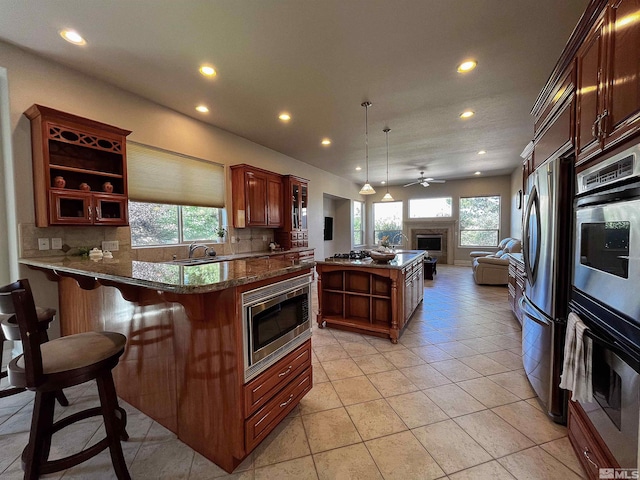 kitchen featuring ceiling fan, stainless steel appliances, backsplash, kitchen peninsula, and a kitchen breakfast bar