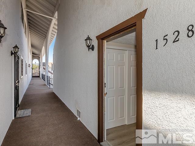 corridor with dark carpet and lofted ceiling