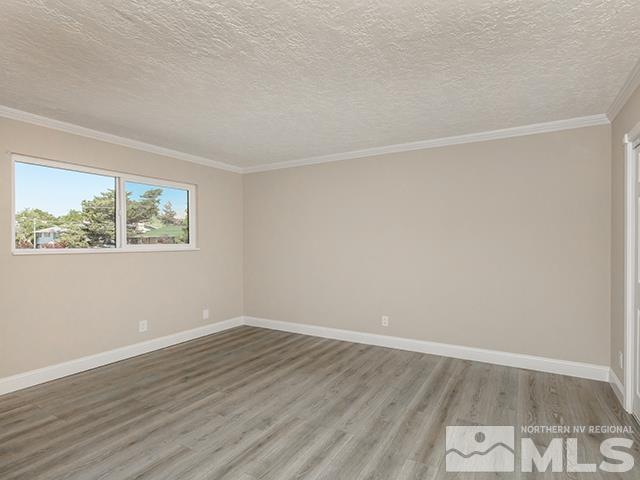 empty room featuring crown molding, wood-type flooring, and a textured ceiling