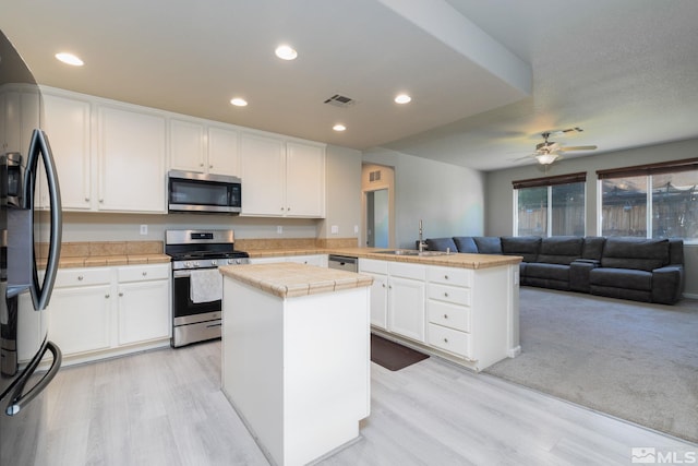 kitchen with a kitchen island, appliances with stainless steel finishes, white cabinetry, sink, and kitchen peninsula