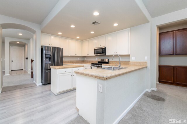 kitchen featuring kitchen peninsula, ceiling fan, appliances with stainless steel finishes, light carpet, and sink