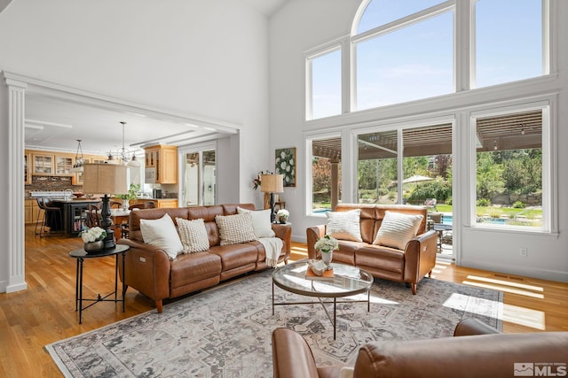 living room with light hardwood / wood-style floors, a healthy amount of sunlight, and a towering ceiling