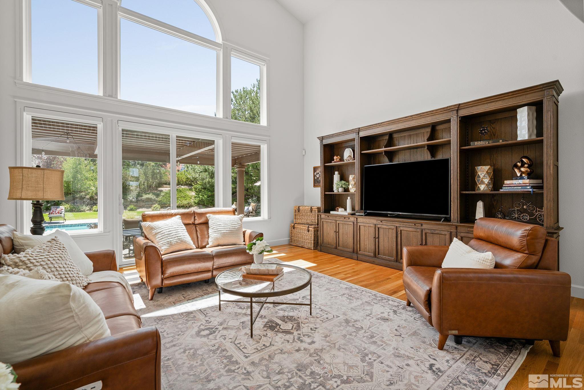 living room with light hardwood / wood-style floors and a towering ceiling