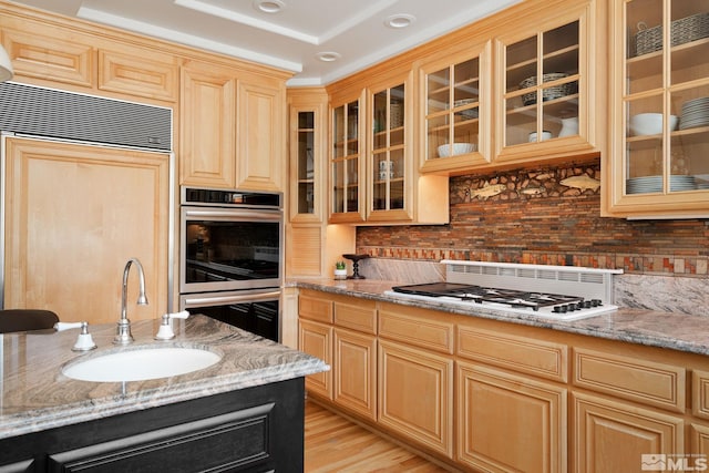 kitchen with light hardwood / wood-style floors, sink, stainless steel double oven, and light stone countertops