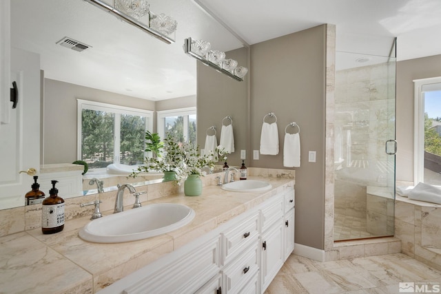 bathroom with tile patterned floors, a shower with door, and dual bowl vanity