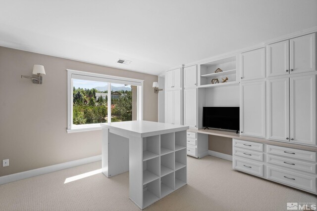 walk in closet with light colored carpet and built in desk