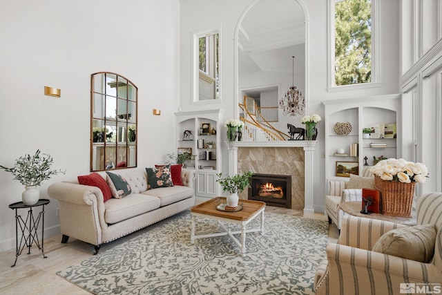 living room with a tile fireplace, a high ceiling, built in shelves, and light tile patterned floors