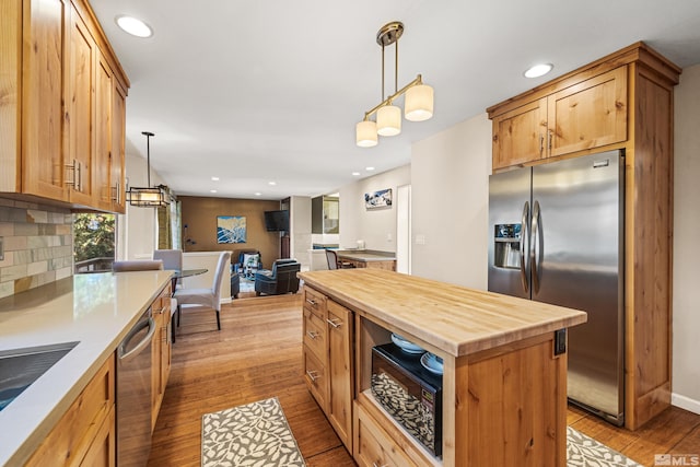 kitchen with stainless steel appliances, decorative light fixtures, butcher block counters, and a kitchen island