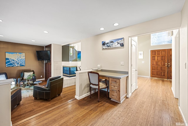 office space with a tile fireplace and light wood-type flooring