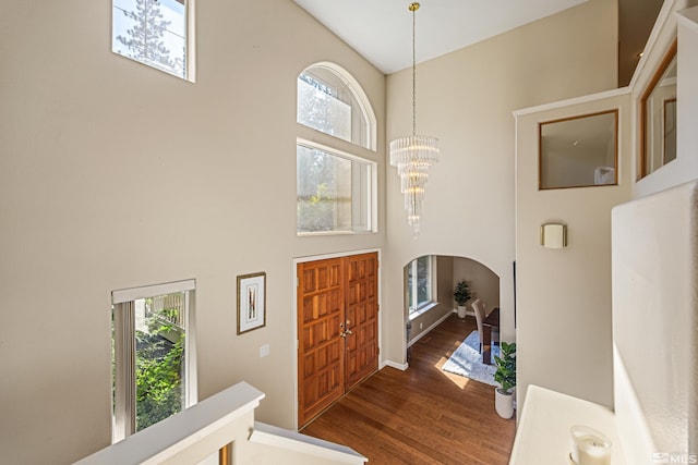 foyer with a towering ceiling, dark hardwood / wood-style flooring, and a notable chandelier