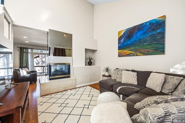 living room featuring a high ceiling, a tile fireplace, and light hardwood / wood-style floors