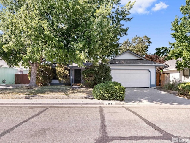 single story home with concrete driveway, a garage, and fence