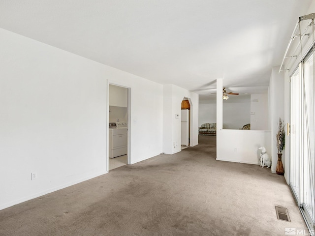 carpeted empty room featuring visible vents, arched walkways, separate washer and dryer, and a ceiling fan