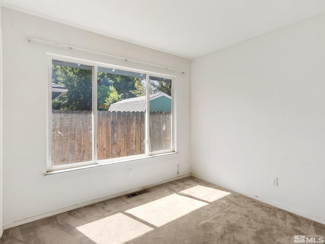 carpeted spare room with plenty of natural light and visible vents