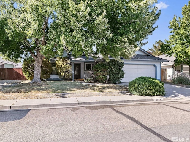 obstructed view of property with concrete driveway, an attached garage, and fence