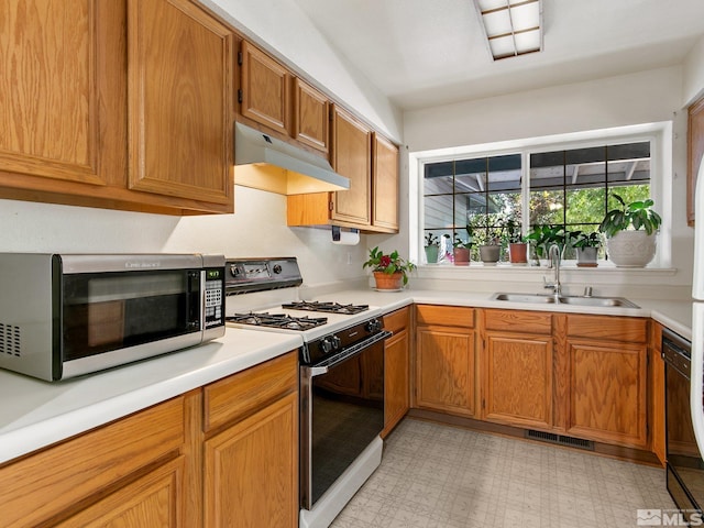 kitchen with visible vents, a sink, under cabinet range hood, range with gas cooktop, and stainless steel microwave