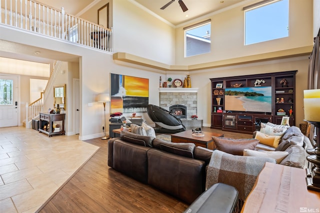 living room with crown molding, ceiling fan, hardwood / wood-style floors, and a towering ceiling